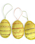 Drei genähte Ostereier aus gelbem Filz mit bunten Ornamenten