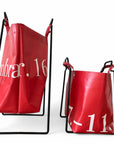 Seitenaufnahme eines grossen und eines kleinen Everyday Design Papiertaschenhalters aus schwarzem Metall mit je einer roten Upcycling Tasche