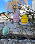 Ostereier aus Filz in rosa, gelb und mintgrün hängen an einem dürren Ast
