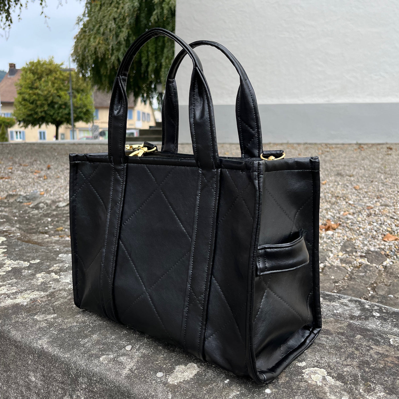 Seitliche Ansicht der schwarzen Tasche aus Kunstleder mit dem typischen Tote Bag Handle 