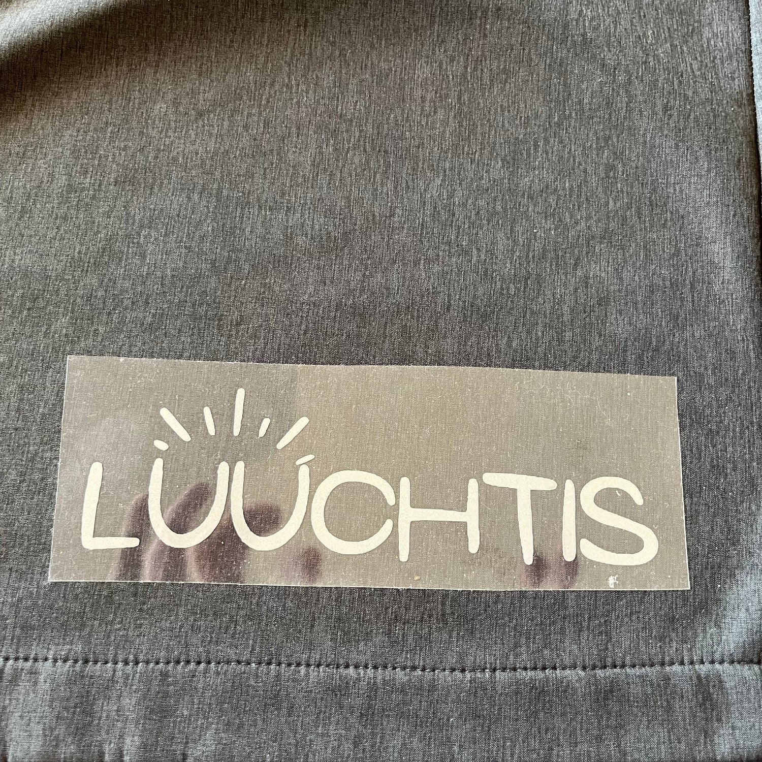 Anbringen der lichtreflektierenden Folie: Positionieren des Lüüchti auf dem Kleidungsstück