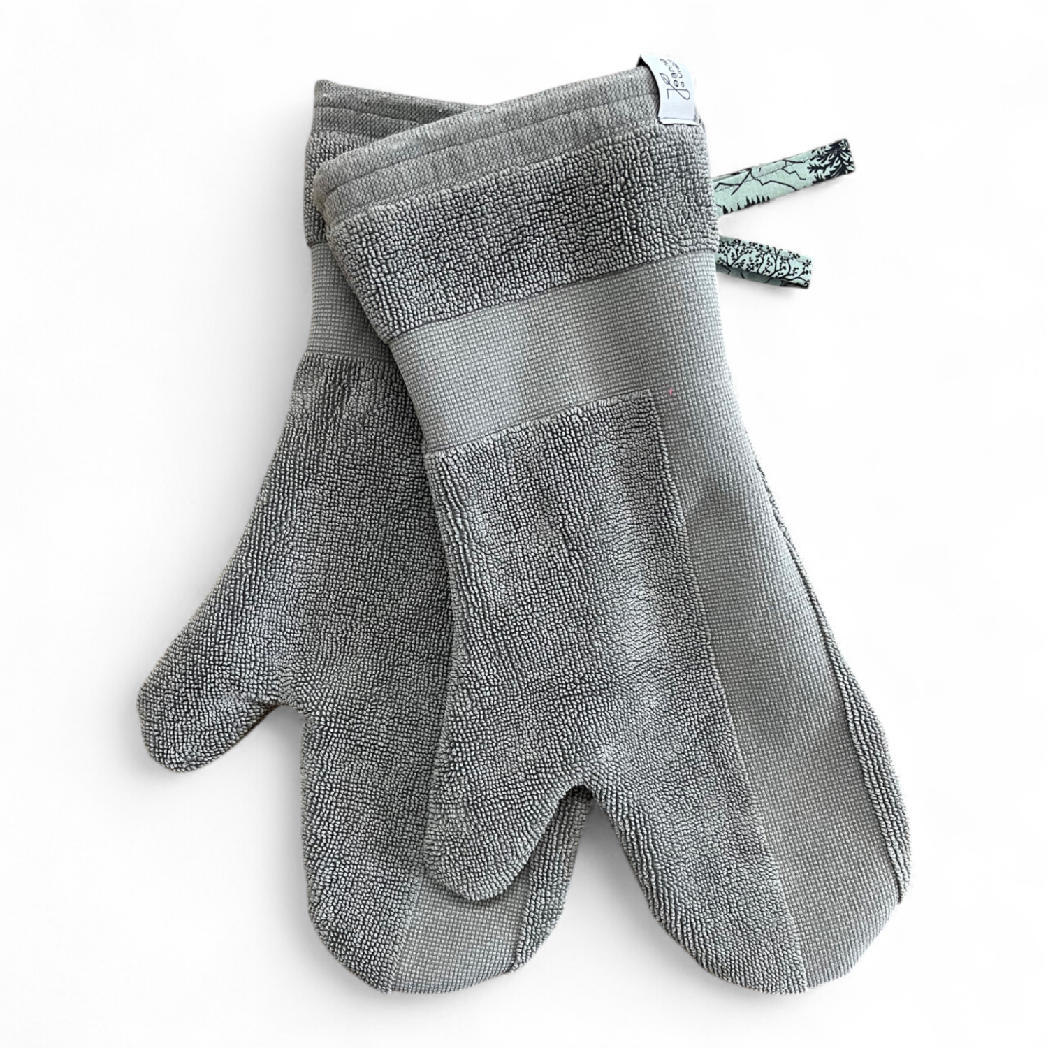 Paar Ofenhandschuhe aus einem umgenähten, hellrauen Badezimmerteppich, gefüttert mit mintgrünem Baumwollstoff mit Folkloremotiv