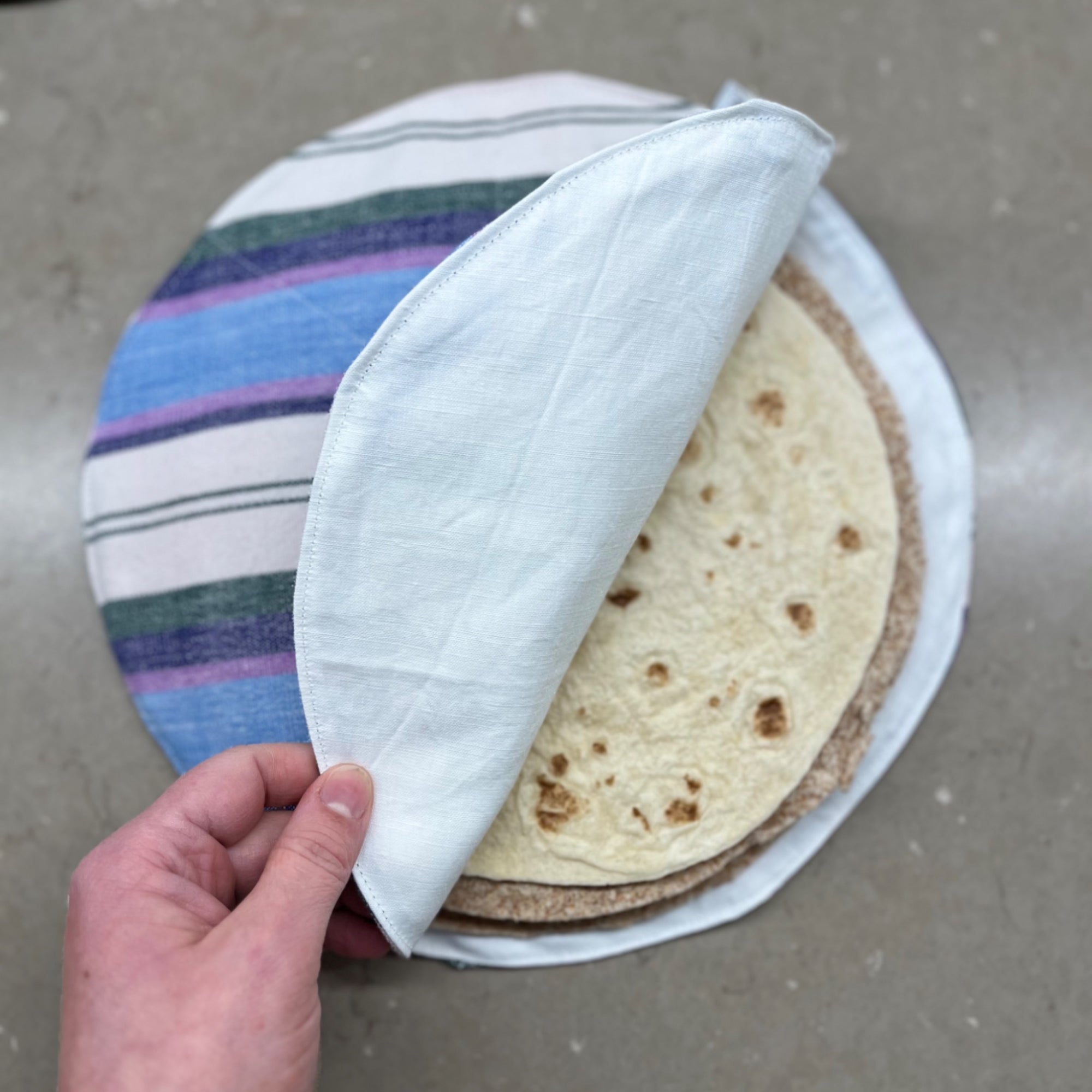 Eine Hand öffnet die Klappe eines Upcycling-Tortillawärmers