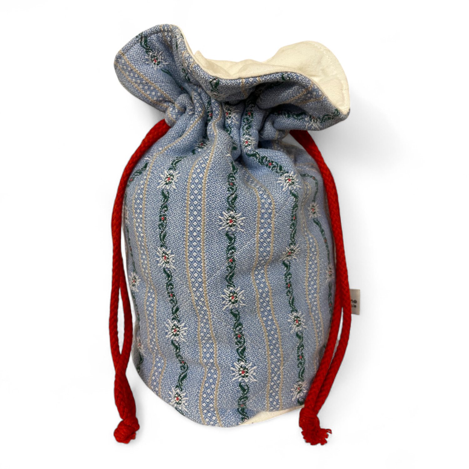 Warmhaltebeutel aus umgenähtem Edelweisshemd. Zugezogen mit roten Kordeln