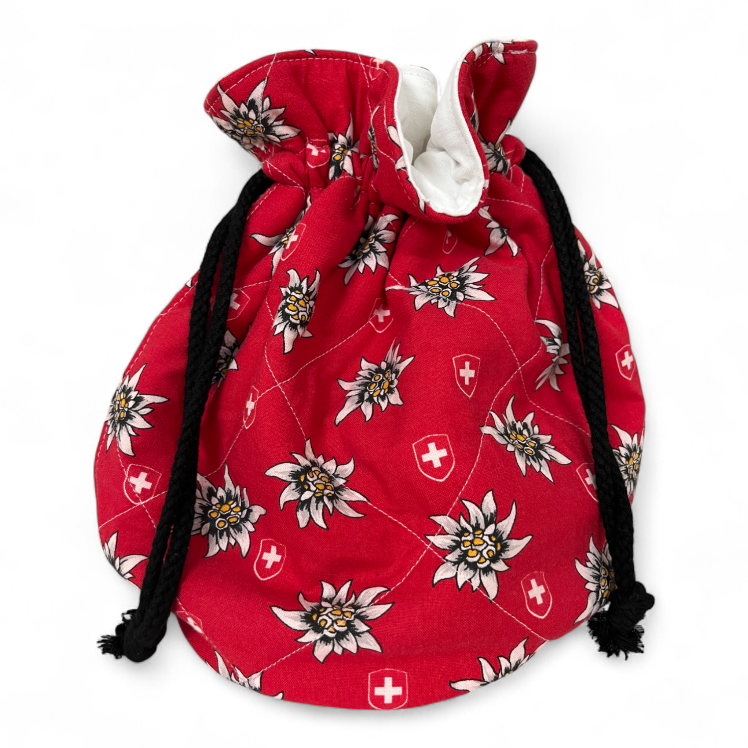 Gschwelltisack aus rotem Stoff mit Edelweissmotiven. Zugezogen mit schwarzen Kordeln.